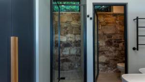 a bathroom with a glass shower in front of a stone wall at Blue Bay Studio Apartment in Wilderness +29 photos