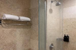 a bathroom with a shower with a glass door at Manna Hotel Pematangsiantar in Pematangsiantar +31 photos