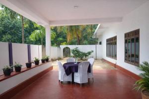 a dining room with a table and white chairs at Premier Stay in Chavakachcheri