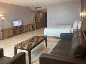 a hotel room with a bed and a couch and a table at Manna Hotel Pematangsiantar in Pematangsiantar