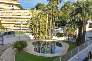 a swimming pool in a yard with palm trees and a building at Apartment Happy Coast Moraira in Moraira