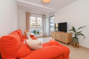 a living room with an orange couch and a flat screen tv at Apartment Happy Coast Moraira in Moraira
