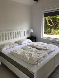 a white bed in a bedroom with a window at Spacious 6p vacation home with garden in Zoutelande