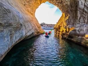 a group of people kayaking through a cave on the water at Sensi Hotel in Marsaskala