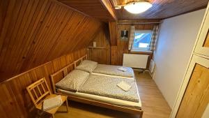 a bedroom with a bed in a wooden room at Chalupa Lázeňka in Pernink