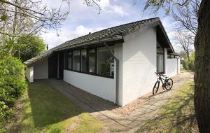 a white house with a bike parked in front of it at Spacious 6p vacation home with garden in Zoutelande
