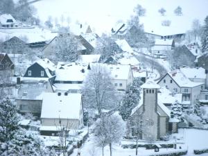 a village covered in snow with a church at Ferienwohnung Hunold in Marsberg