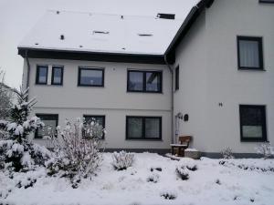 a large white house with snow in front of it at Ferienwohnung Hunold in Marsberg +6 photos
