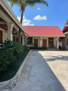 a house with a red roof and a palm tree at ksana guesthouse in Luang Prabang