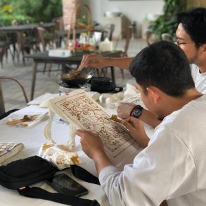 a group of men sitting at a table eating food at "D'BAMBOO KAMP" Desa Wisata Ekang in Lagoi