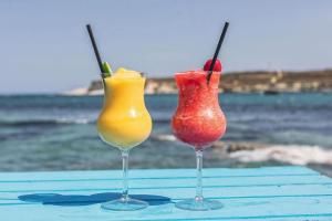 two cocktails sitting on a table on the beach at Sensi Hotel in Marsaskala
