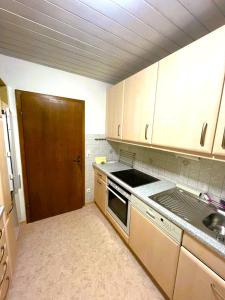 a kitchen with white cabinets and a sink and a door at Gemütliche Maisonette nahe der längsten Burg der Welt in Burghausen +11 photos
