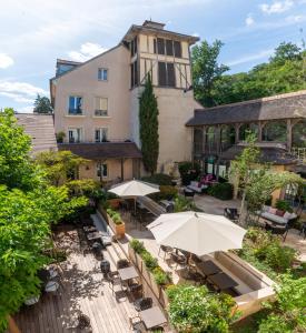 an outdoor patio with tables and umbrellas in front of a building at Les Etangs de Corot in Ville-dʼAvray