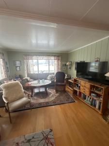 a living room with a tv and a couch and a table at Helt hjem i lyngen in Lyngen