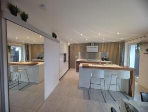an open kitchen with white counters and bar stools at La Chataigneraie in Châtenois