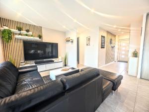 a living room with a black leather couch and a flat screen tv at La Chataigneraie in Châtenois