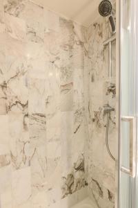 a bathroom with a shower with white marble walls at Studio Cosy - Le Marais centre in Paris