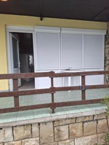 two windows with white blinds on a porch at Juci Home Apartman in Vonyarcvashegy