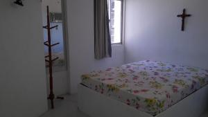 1 dormitorio con 1 cama con una cruz en la pared en Apartamento ponta verde Cote en Maceió
