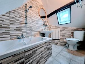 a bathroom with a tub and a toilet and a sink at La Croix Duplex - Bail Partner in Chablis