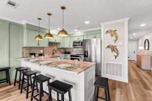 a kitchen with green cabinets and a large island with stools at C' Salt 10B in Destin