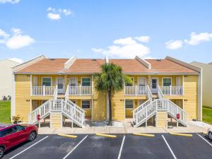 a yellow apartment building with a palm tree in a parking lot at C' Salt 10B in Destin