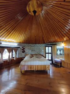 a bed in a room with a wooden ceiling at Khali Estate in Binsar