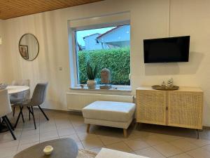 a living room with a tv and a window at ZweiundMeer Bungalow 2 in Wiek auf Rügen