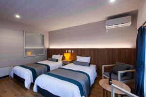 a hotel room with two beds and a chair at MONTIS HOTEL Hida Takayama in Takayama