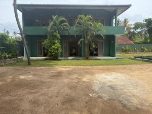 a green house with palm trees in front of it at Sea Station in Habaraduwa Central
