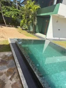 a swimming pool with blue water in front of a building at Sea Station in Habaraduwa Central