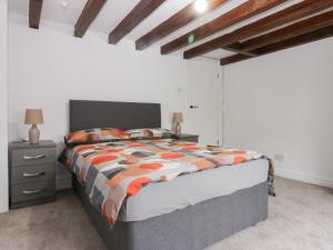 a bedroom with a bed with an orange and white comforter at Chandlers Cottage in Conwy