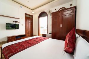 a bedroom with a large white bed with red pillows at Collection O Long Phung Hotel in Ho Chi Minh City