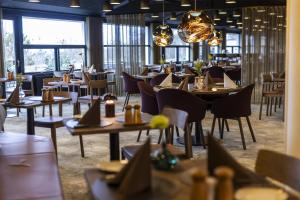 ein Restaurant mit Tischen, Stühlen und Fenstern in der Unterkunft Scandic Aalborg Øst in Aalborg + 21 Fotos