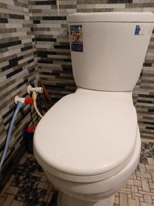 a white toilet sitting in a bathroom next to a wall at Social Stay Hostal in Ahangama