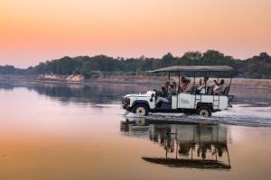 a group of people riding in a jeep in the water at Msandile River Lodge in Kakumbi
