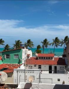 a view of a building with palm trees and the ocean at Pousada LuMar Maragogi in Maragogi