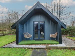 a small blue shed with two chairs in it at Glamping Tri Pod 2 - Gower in Swansea
