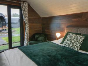 a bedroom with a bed and a chair and a window at Glamping Tri Pod 2 - Gower in Swansea
