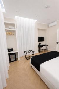 a white bedroom with a bed and a desk at SOFIA Suites & Rooms in Pompei