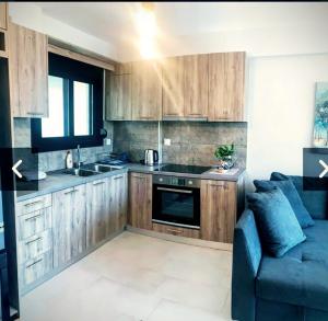 a kitchen with wooden cabinets and a blue couch at EXOTIC LUXURY APARTMENT in Nikiana