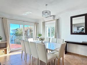 a dining room with a table and white chairs at 5 Bedroom Villa with HEATED Pool with breath-taking Sea Views, Walking distances to Shops Restaurants Beach in Manilva