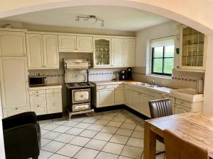 a kitchen with white cabinets and a table in it at Buitenplaats 67 with optional sauna in Callantsoog