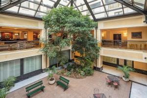 an indoorrium with benches and a tree in a building at Starhotels Du Parc in Parma