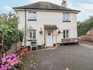 a white house with a bench in front of it at Orchard Cottage in Dawlish