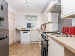 a kitchen with white cabinets and a red appliance at Orchard Cottage in Dawlish
