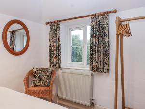 a bedroom with a chair and a window at Orchard Cottage in Dawlish