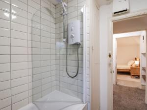 a shower in a bathroom with white tiles at Orchard Cottage in Dawlish +17 photos