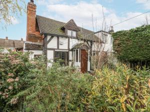 an old white house with a hedge at Magpie Cottage in Worcester