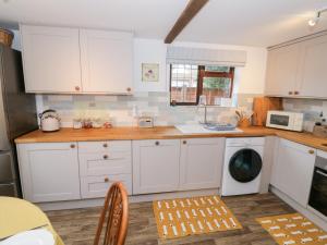 a kitchen with white cabinets and a washing machine at Magpie Cottage in Worcester